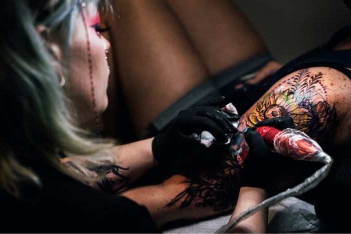 Lacey tattooing a shoulder